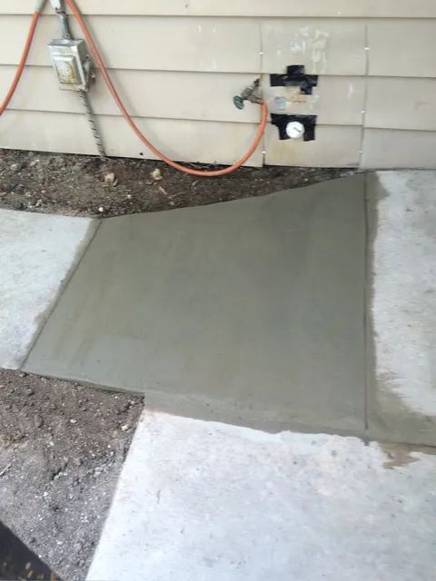 Freshly poured concrete pad against a wall