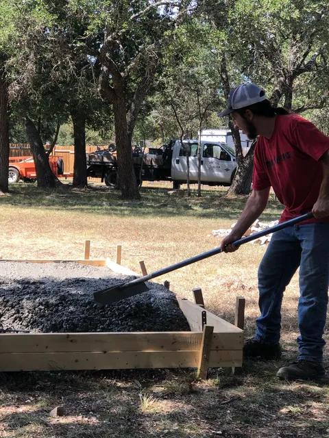 Raking concrete into forms on a rural job