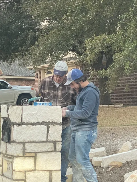 Masons building a stone mailbox column