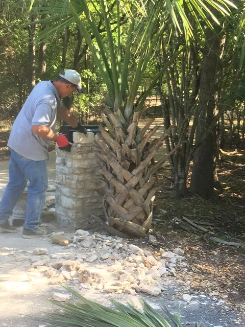 Mason shaping a stone column by hand