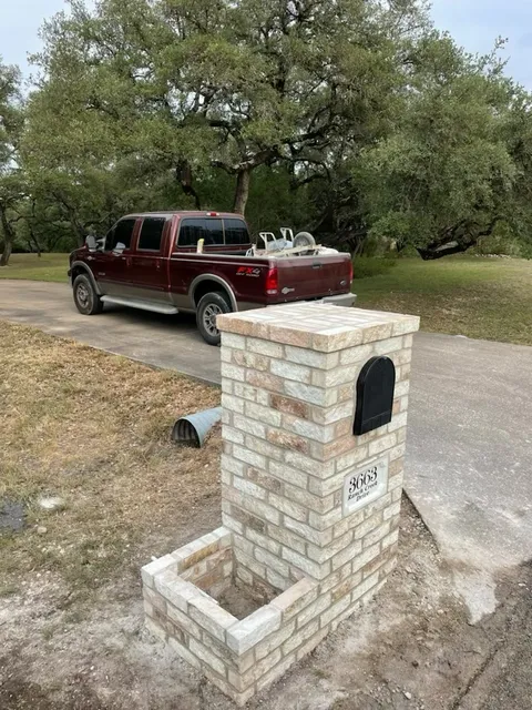 Stone mailbox and planter along a driveway