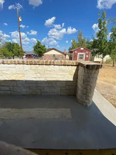 Low stone seat wall beside a concrete patio