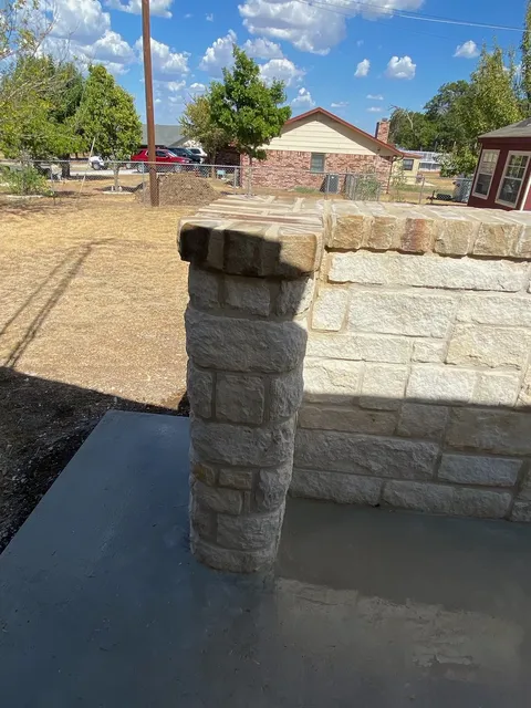 Round stone column beside fresh concrete flatwork